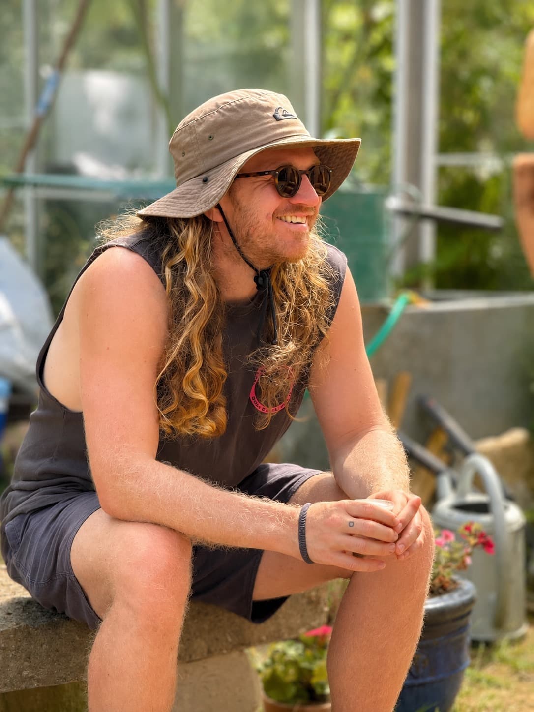 James Newton smiling in a garden, wearing a sun hat