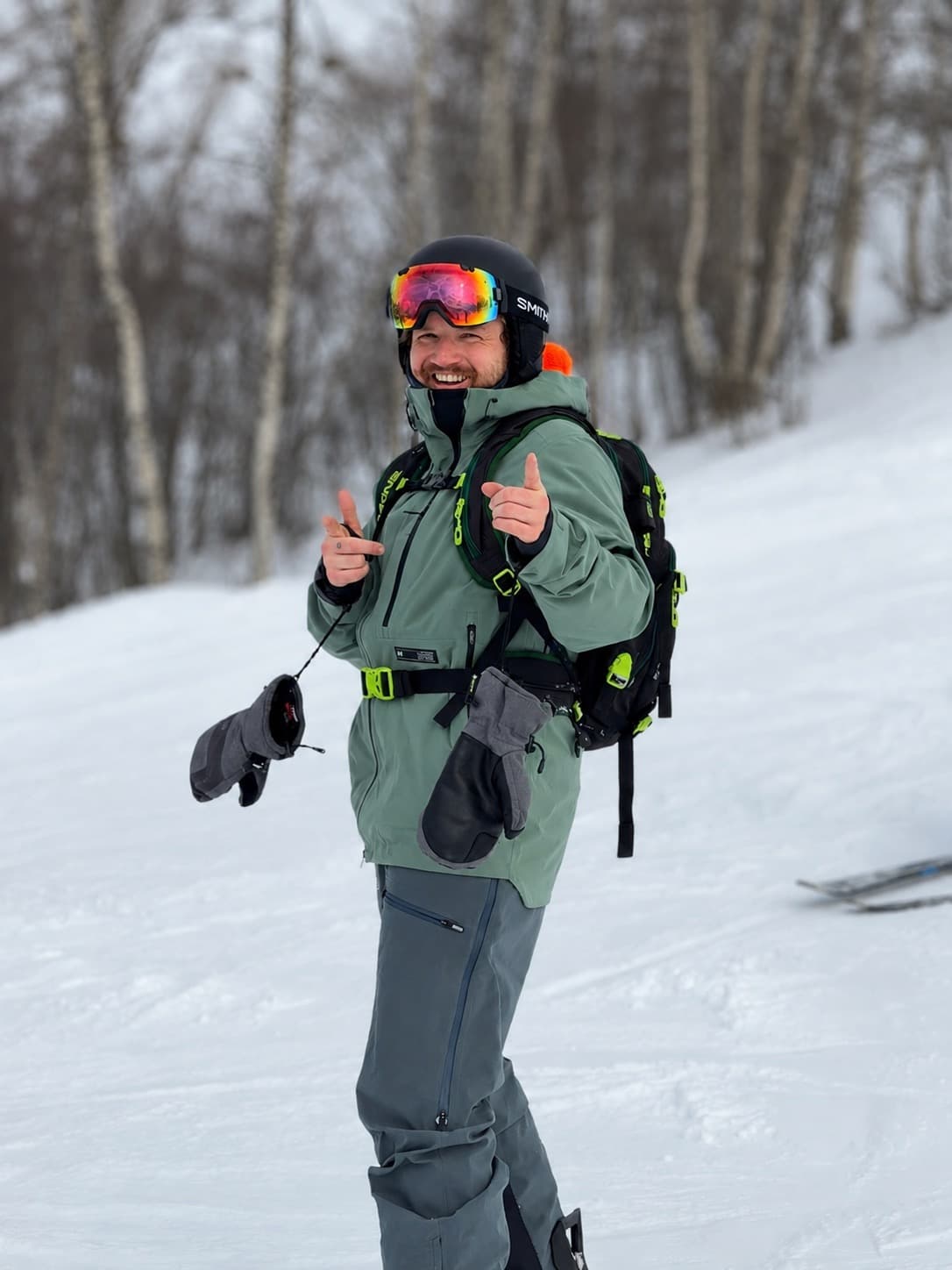 James Newton skiing down a snowy mountain, giving a thumbs up